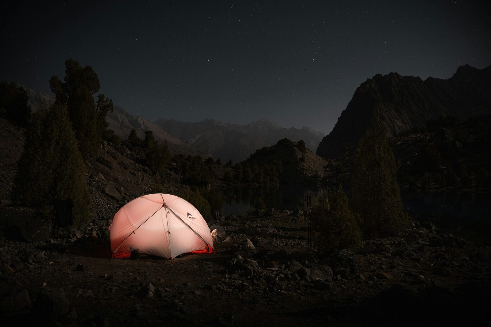 A red and white tent sitting on top of a rocky hillside